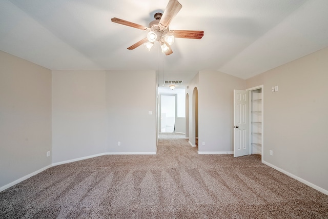 unfurnished room featuring arched walkways, carpet flooring, visible vents, baseboards, and vaulted ceiling