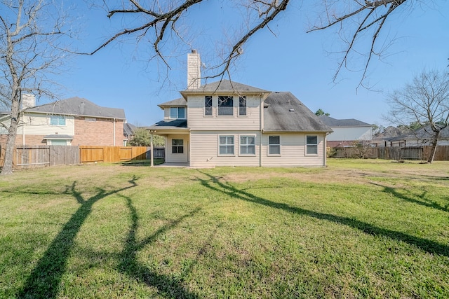 back of house with a chimney, a fenced backyard, and a lawn