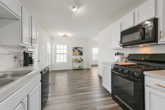 kitchen featuring decorative backsplash, light countertops, light wood-type flooring, black appliances, and white cabinetry