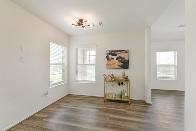 unfurnished dining area with plenty of natural light, wood finished floors, and an inviting chandelier