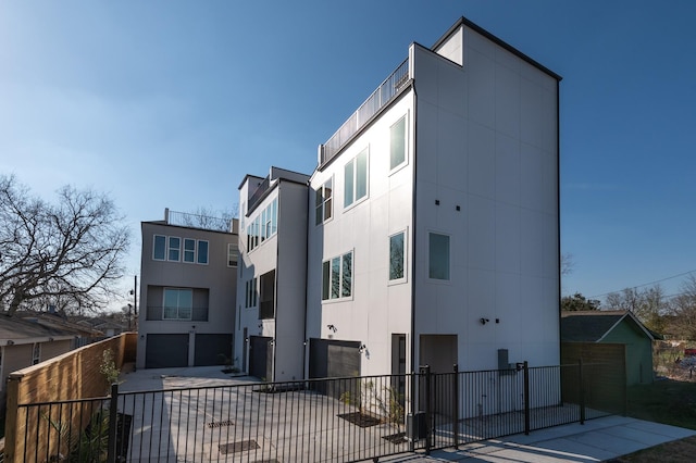 view of building exterior featuring a garage, fence, and concrete driveway