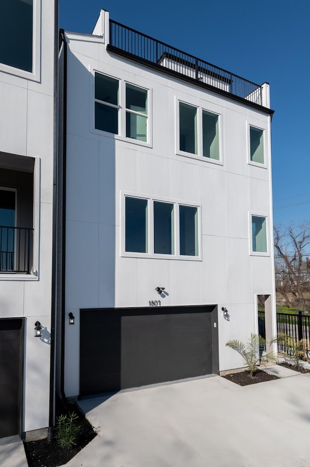 view of front of house with driveway, fence, and stucco siding