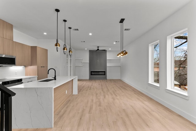 kitchen featuring visible vents, modern cabinets, stainless steel microwave, and a sink