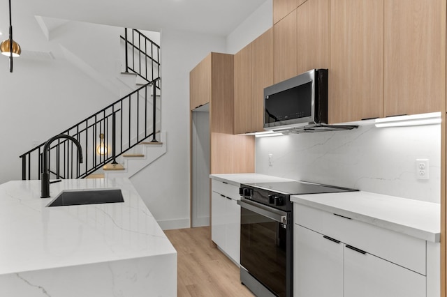 kitchen with stainless steel microwave, black range with electric stovetop, a sink, and modern cabinets