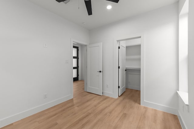 unfurnished bedroom with baseboards, a walk in closet, light wood-type flooring, a closet, and recessed lighting