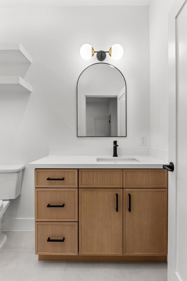 bathroom featuring baseboards, vanity, toilet, and tile patterned floors