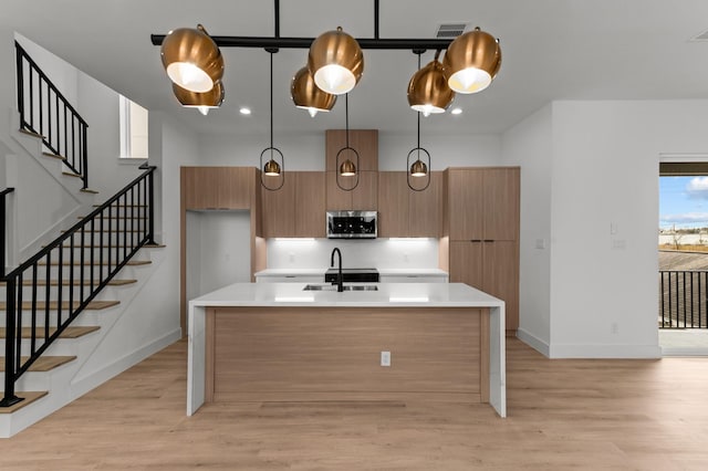 kitchen featuring light wood-type flooring, modern cabinets, stainless steel microwave, and light countertops