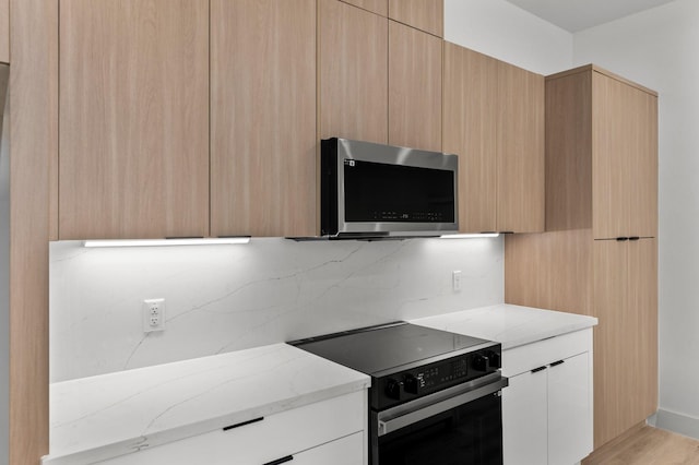 kitchen with range with electric cooktop, stainless steel microwave, modern cabinets, and light stone countertops