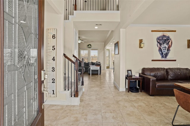 foyer with light tile patterned floors, baseboards, visible vents, a high ceiling, and stairs