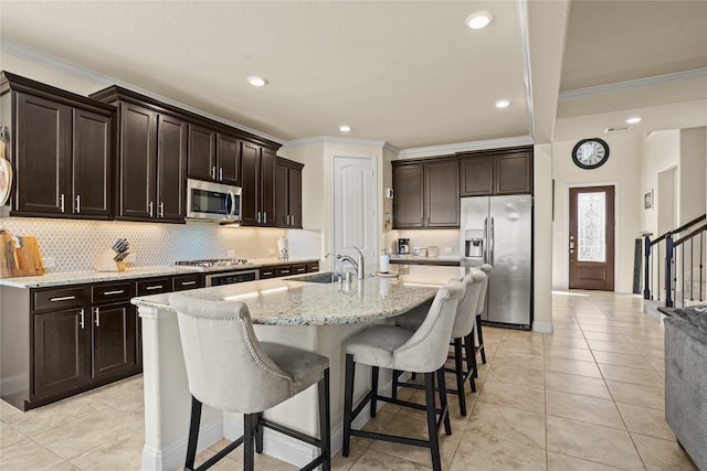 kitchen featuring stainless steel appliances, a sink, a kitchen bar, and ornamental molding