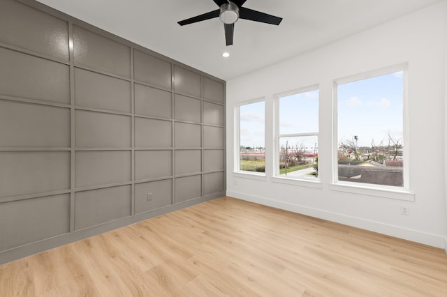 interior space featuring baseboards, ceiling fan, wood finished floors, and a decorative wall