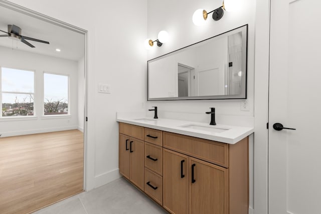 full bathroom featuring double vanity, a sink, a ceiling fan, and baseboards