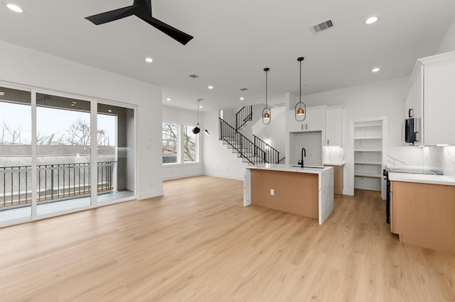 kitchen featuring visible vents, ceiling fan, appliances with stainless steel finishes, open floor plan, and light wood-type flooring