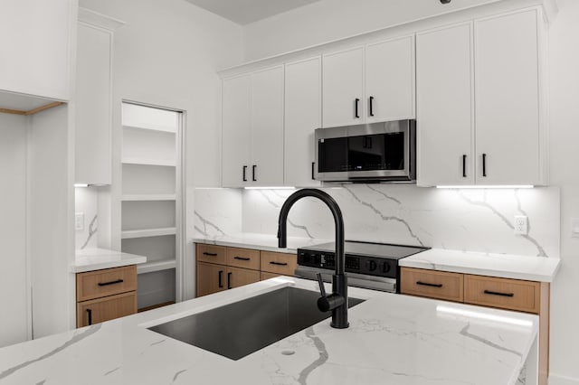 kitchen with decorative backsplash, light stone counters, stainless steel appliances, and a sink