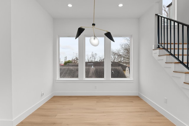 unfurnished dining area featuring recessed lighting, stairway, light wood-type flooring, and baseboards