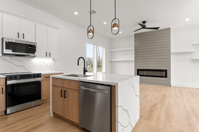 kitchen with a large fireplace, a sink, visible vents, appliances with stainless steel finishes, and backsplash