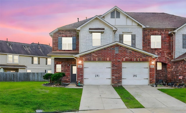 view of front of house featuring driveway, an attached garage, fence, a yard, and brick siding