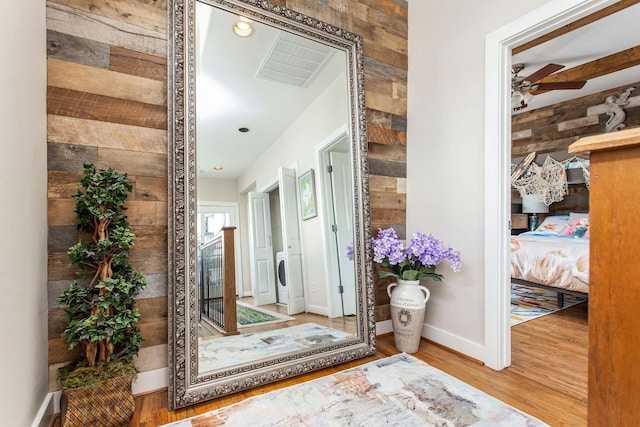 hallway featuring visible vents, wooden walls, baseboards, recessed lighting, and wood finished floors