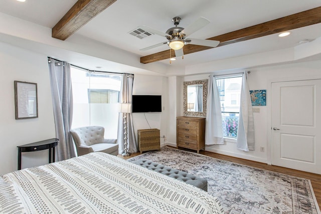 bedroom with beam ceiling, wood finished floors, visible vents, and baseboards