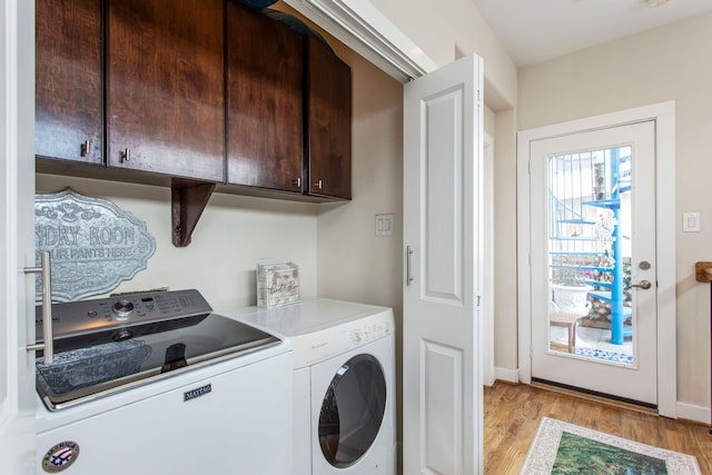 washroom featuring cabinet space, washing machine and dryer, light wood-type flooring, and baseboards