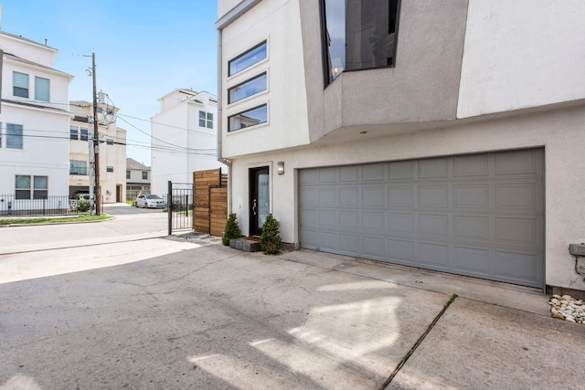 garage featuring concrete driveway and fence