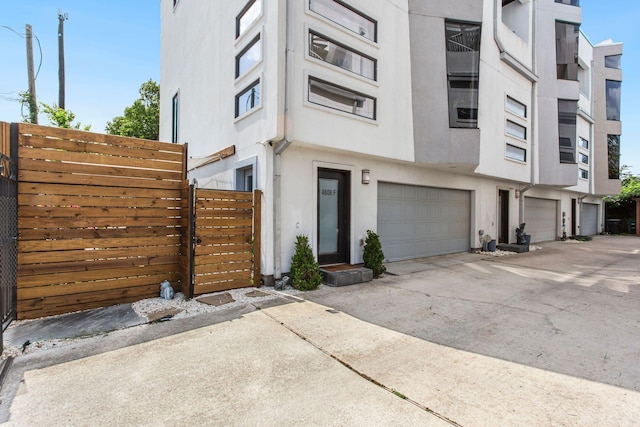 view of property featuring stucco siding, an attached garage, driveway, and fence