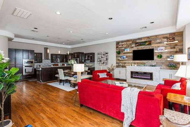 living room with recessed lighting, visible vents, a glass covered fireplace, and wood finished floors