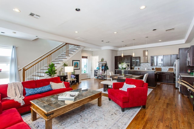 living room with dark wood-style floors, visible vents, recessed lighting, and stairway