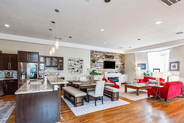 living room with a glass covered fireplace, visible vents, wood finished floors, and recessed lighting