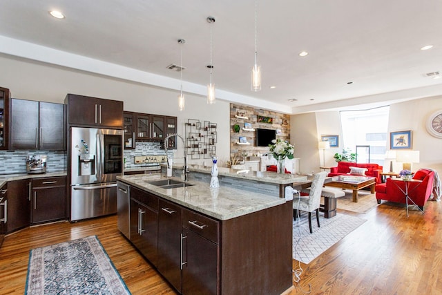 kitchen featuring wood finished floors, stainless steel appliances, open floor plan, and a sink