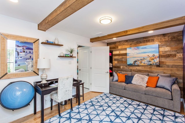 living area with beam ceiling, wood walls, and wood finished floors