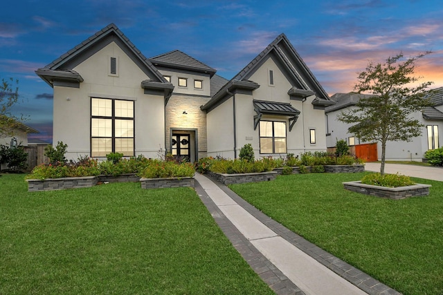 view of front of home with stone siding, a yard, fence, and stucco siding