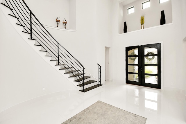 entryway featuring french doors, stairway, and a towering ceiling