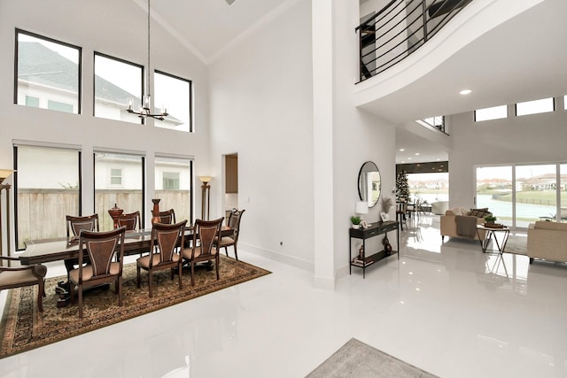 dining room featuring a chandelier, a high ceiling, a water view, and baseboards