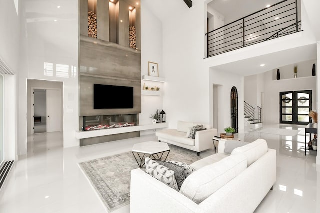 tiled living area with french doors, stairway, and a towering ceiling