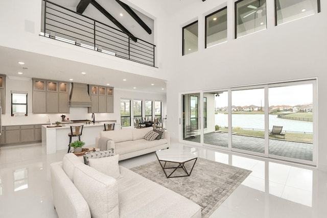 living room featuring recessed lighting, a water view, beamed ceiling, and a towering ceiling