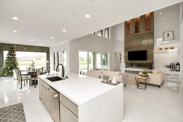 kitchen featuring recessed lighting, open floor plan, a kitchen island with sink, a sink, and dishwasher