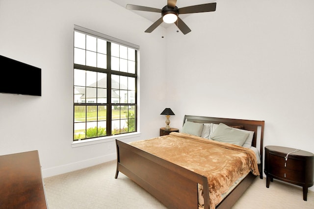 bedroom featuring light carpet, baseboards, and a ceiling fan