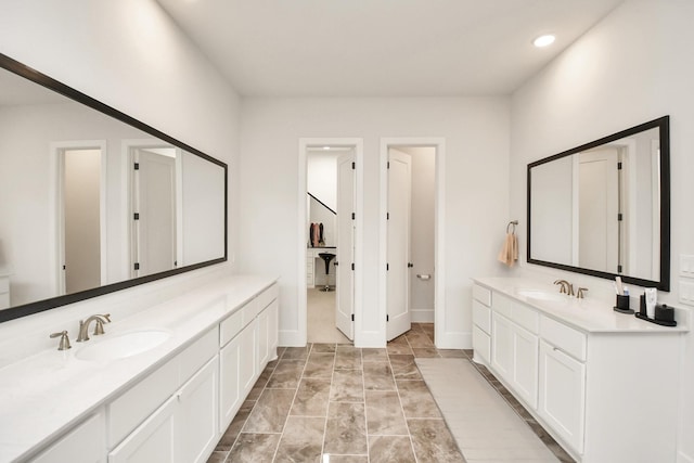 bathroom with recessed lighting, two vanities, a sink, and baseboards