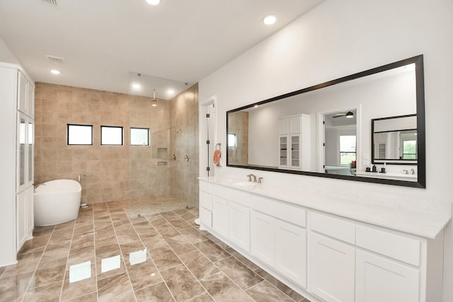 bathroom with recessed lighting, a walk in shower, a freestanding bath, and vanity