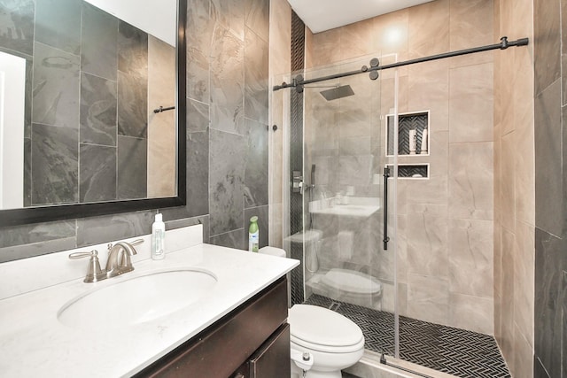 bathroom featuring a stall shower, tile walls, vanity, and toilet