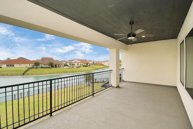 balcony with a water view, a residential view, and a ceiling fan