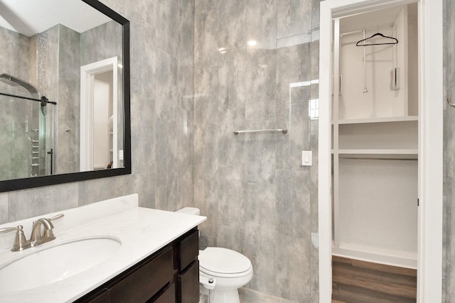 full bath featuring toilet, a spacious closet, vanity, and tile walls