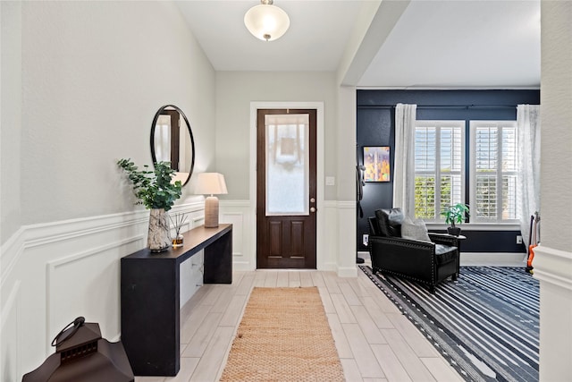 foyer with wood tiled floor and a wainscoted wall