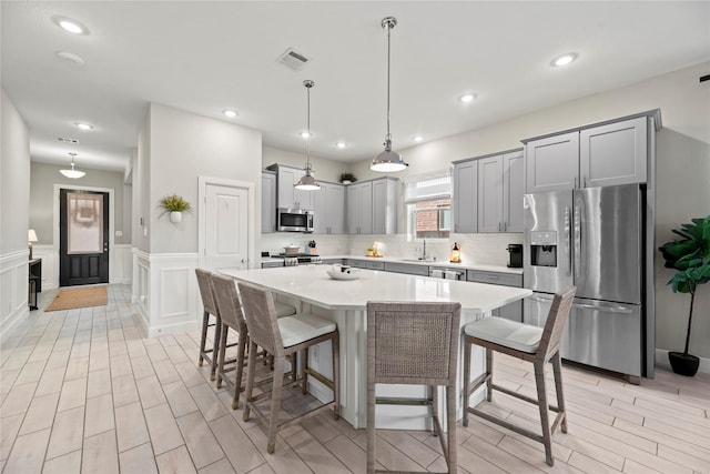 kitchen with stainless steel appliances, tasteful backsplash, light countertops, visible vents, and a kitchen bar