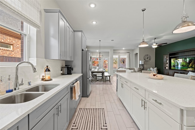 kitchen with a sink, open floor plan, appliances with stainless steel finishes, decorative backsplash, and decorative light fixtures