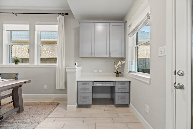 office area featuring a healthy amount of sunlight, baseboards, and built in study area