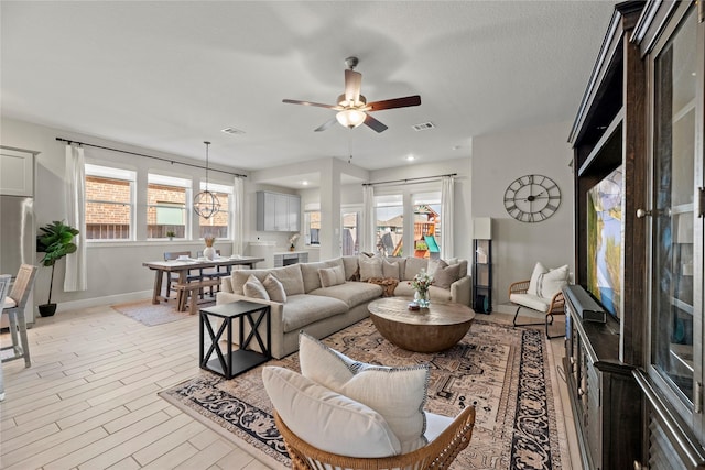 living room with a ceiling fan, visible vents, light wood-style flooring, and baseboards