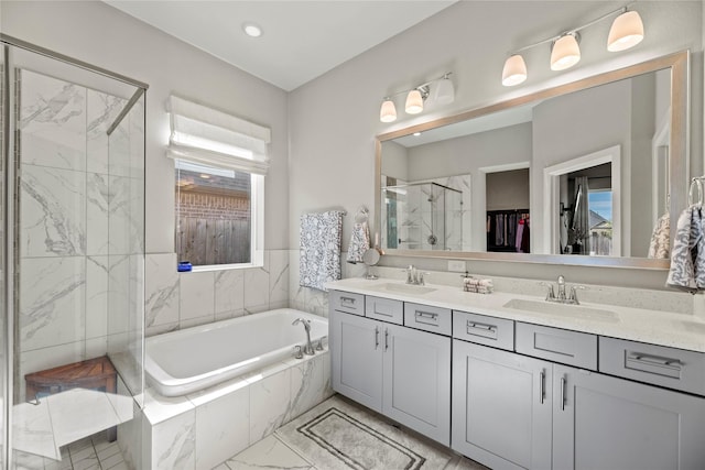 bathroom with double vanity, a garden tub, a shower stall, and a sink