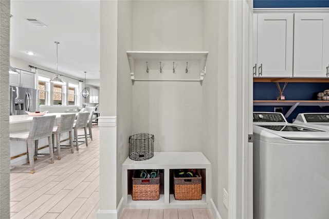 mudroom with wood tiled floor, visible vents, and separate washer and dryer